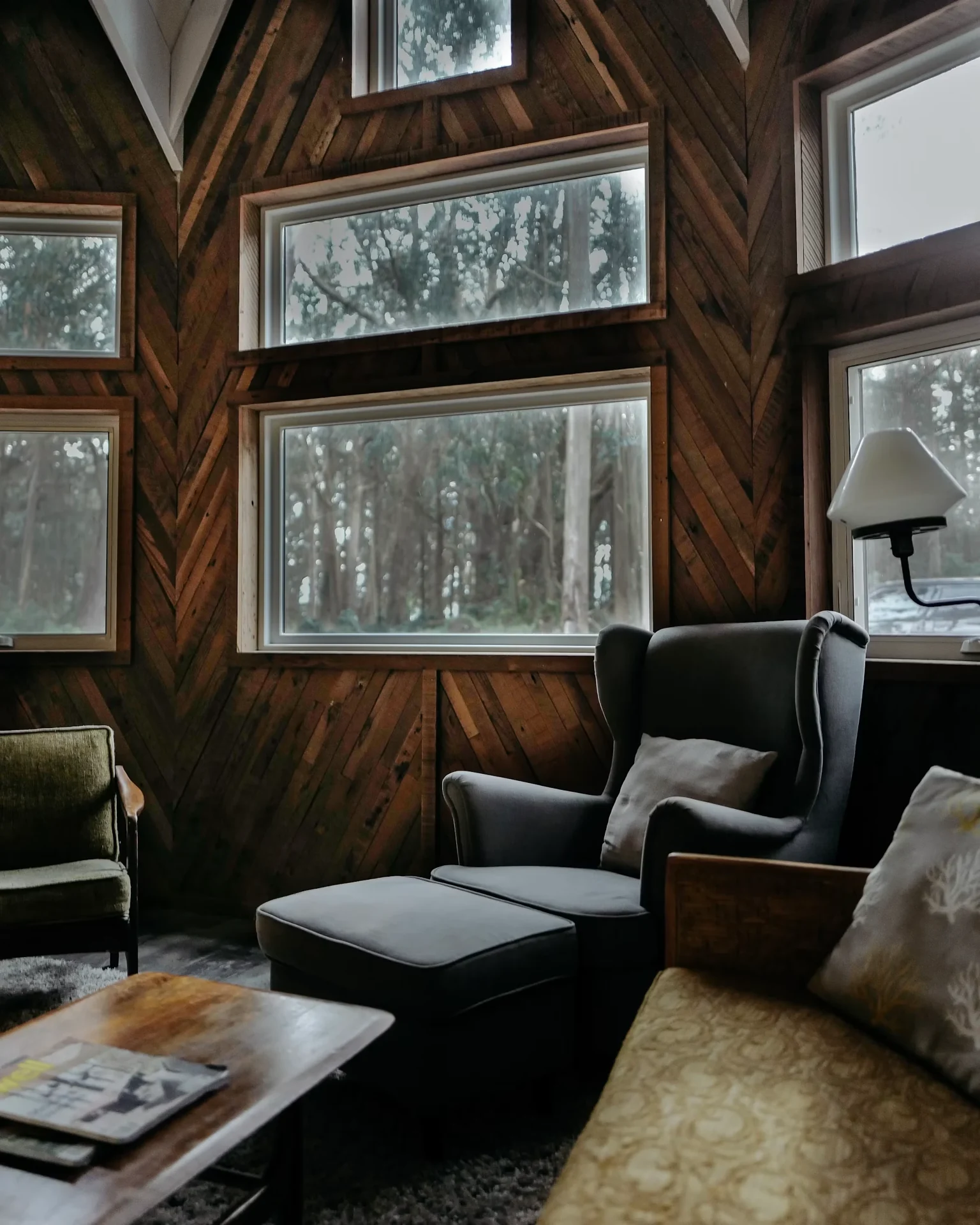 Reading nook beside a tall forest-facing window